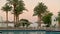 Resort with palm trees and pool at sunset. Beautiful luxurious swimming pool in tropical resort