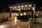 A resort style backyard at night with a waterfall, pergola, and a firepit