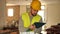 Responsible focused young bearded supervisor wearing yellow safety vest and hard hat taking notes on papers while