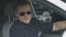 Responsible policeman in sunglasses sitting in patrol car, smiling to camera