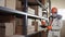 Responsible worker in a helmet and overalls stands next to the racks and remove box for right inventory with the tablet