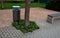 Rest area with park bench and ornamental cherry trees. the surface is made of beige fine gravel, square flowerbeds with perennials