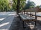Rest area in a park with paved path and resting bench with trees