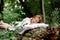 Rest, relaxation in the forest. A woman lies on a pillow on a tree surrounded by green foliage