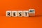 Rest and restart symbol. Turned a wooden cube and changed the word rest to restart. Beautiful orange table, orange background,