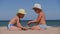 Rest on the sea with children. Sand is poured from the palms of the hands into the palms of the child. Two boys in hats