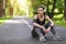 Rest After Training Outdoors. Young Asian Woman In Headphones Sitting On Path