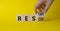 Restart Rescue symbol. Hand turns cubes and changes the word Rescue to Restart. Beautiful yellow background. Businessman hand.