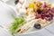 Restaurant cheese plate - various types of cheeses with grapes and black olive on white plate. Close up image with selective focus