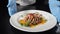 Restaurant chef demonstrating ready-made plate with juicy sliced meat, vegetables poured with sweet sauce. Fine cuisine