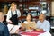 Restaurant guests will choose dish from the menu. Polite waitress helps with choice