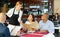 Restaurant guests will choose dish from the menu. Polite waitress helps with choice