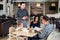 Restaurant and holiday concept - waiter giving menu to happy family at cafe