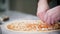 Restaurant kitchen. A chef putting cheese pieces on the pizza