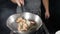 Restaurant kitchen concept. Chef tosses deep-fried shrimps in frying pan on black background. Chef tossings, mixing and