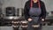 in a restaurant kitchen, a woman piles up prepackaged meals with healthy food in a plastic package on a metal table in a