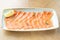 Restaurant menu. Plate with slightly salted and smoked salmon or trout fillet on wooden table background. Thin slices of