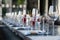 Restaurant serving, glass wine and water glasses, forks and knives on textile napkins stand in a row on a gray wooden table.