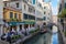 Restaurant with sidewalk tables with people in Venice, canal with gondola in Italy