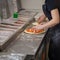 Restaurant workers make pizza, laying on the base of pizza the grated cheese and slices of tomatoes