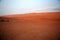 The resting of the herd of camels, in the distance, at sunset in the red desert of Oman, Wahiba Sands / Sharqiya Sands, Oman