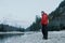 Resting mountaineer with alpinist backpack and equipment standing on pebble river bank at winter evening rocky landscape