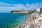 Resting people on the sandy Pizana beach against the background of the fortress walls of the citadel of the old town of Budva.