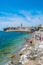 Resting people on the sandy Pizana beach against the background of the fortress walls of the citadel of the old town of Budva.