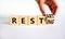 Resting and restart symbol. Businessman turns a wooden cube and changes the word resting to restart. Beautiful white table, white