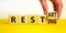 Resting and restart symbol. Businessman turns a wooden cube and changes the word resting to restart. Beautiful yellow table, white