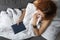 Resting woman. Young ginger girl on the sofa under blanket reads book. Top view