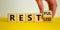 Restless or restful symbol. Businessman turns the wooden cube, changes the word `restless` to `restful`. Beautiful yellow tabl