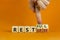 Restless or restful symbol. Businessman turns wooden cubes, changes the word `restless` to `restful`. Beautiful orange table,