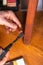 Restoration of wooden furniture. master fixes a scratch on the table leg with a wax pencil and a soldering iron close-up