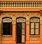 A restored orange Chinese peranakan shop house with brown shutters