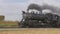 Restored steam locomotive passing by with passenger car blowing smoke and steam thru countryside