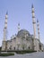 Restored white mineral mosque with four minarets against a blue sky