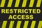 Restricted access text warning sign with yellow and black stripes painted over cracked wood