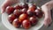 Retail and business, ripe black tomatoes on a plate in the hands of a woman.