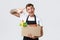 Retail, grocery shopping and delivery concept. Handsome courier in black apron handing over box with groceries, salesman