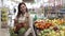 Retail store, beautiful smiling shopper woman with shopping basket chooses eco-friendly products fruits and vegetables