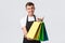 Retail store, shopping and employees concept. Friendly handsome smiling salesman, shop assistand in black apron give out