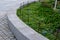 Retaining seat wall made of pure cast concrete blooms purple flowers behind it the wall is bordered by metal fences with black rop