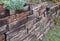 The retaining wall made of wooden sleepers is wooden and forms the edge of the perennial flowerbed. landscaping of brown palisade