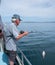 Retired adult man fishing on charter boat, catching a snapper -