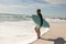 Retired biracial senior man carrying surfboard walking on shore at beach during sunny day