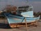 Retired boat resting on shore on stands