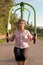 Retired brazilian woman with sportswear training chest and shoulder in gym equipment. Outside in park and woods. Active,