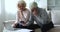 Retired couple calculate bills, experiencing financial difficulties, feel stressed