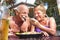 Retired couple having fun eating local food at thai restaurant beach bar outdoors - Mature man and woman on active elderly